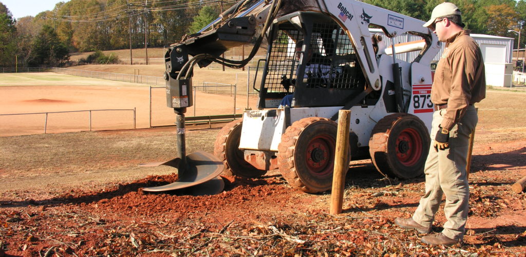 A skid loader with a 36-inch auger digs the holes for planting B&B trees.