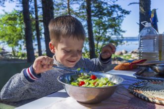A preschooler helping mix a salad.