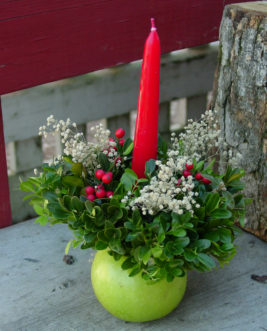 An apple makes a great base for a candle surrounded by boxwood, nandina berries, and baby’s breath. 