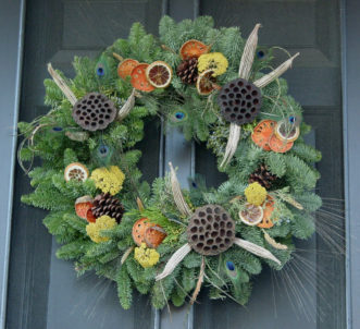 Dried oranges and yarrow, okra and lotus pods, peacock feathers, and barley adorn a spruce wreath.