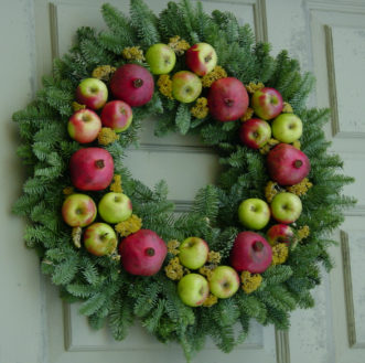 The addition of fresh fruit and dried flowers add interest to a fresh Fraser fir wreath.