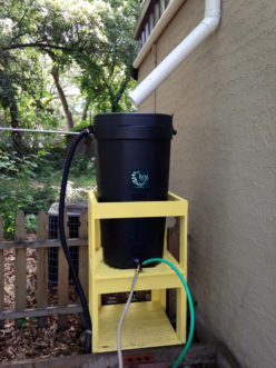 Figure 2. Both of these rain barrels are elevated using a wooden stand to provide head pressure so that water will move from the barrel to the point of use. The barrels are either enclosed or strapped to the wooden stand for stability and safety purposes. 