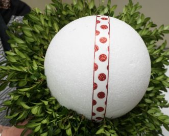 The boxwood sprigs should be placed closely together where you can’t see any white on the ball.