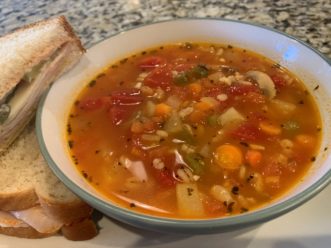The finished roasted vegetable and barley soup served with a sandwich.