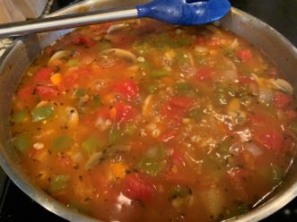 The roasted vegetable and barley soup simmers until the barley is tender.