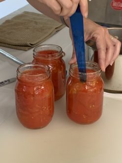 Removing air bubbles from a jar of hot pack tomato halves.