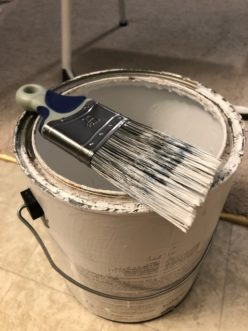 Reduce the amount of paint left on the brush by pressing the bristles against the side of the container to squeeze out any remaining paint. Jessica Moore, ©2020, Clemson University