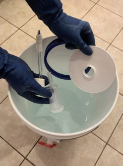 Adding parts to a sanitizer bucket.