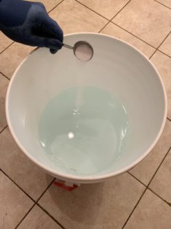 Adding Powdered Brewery Wash (PBW) to a brewing bucket of clean, potable water.