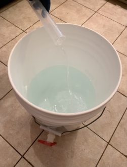 Adding stock sanitizer to a brewing bucket of clean, potable water.