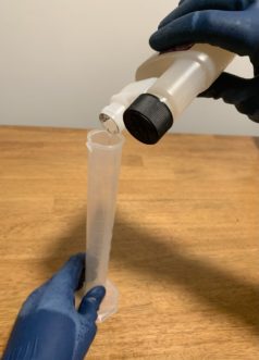 Measuring out stock sanitizer into a graduated cylinder.