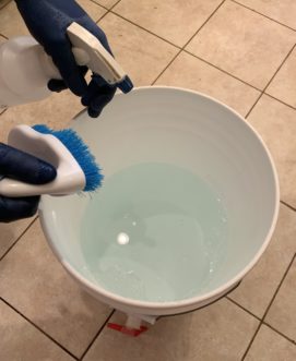 Using dilute sanitizer from a spray bottle on a brew bucket.