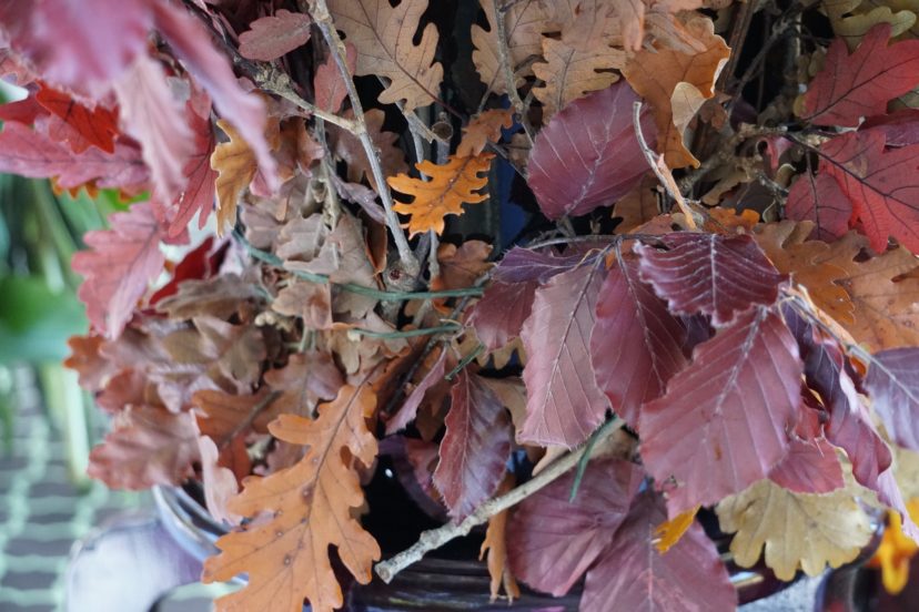 Ms. Dowling ran a floral wire around a plastic floral bucket, then inserted autumn leaf branches to cover the container. This created another textural element to her design.