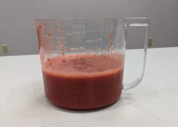 Pureed strawberries in a clear measuring cup.