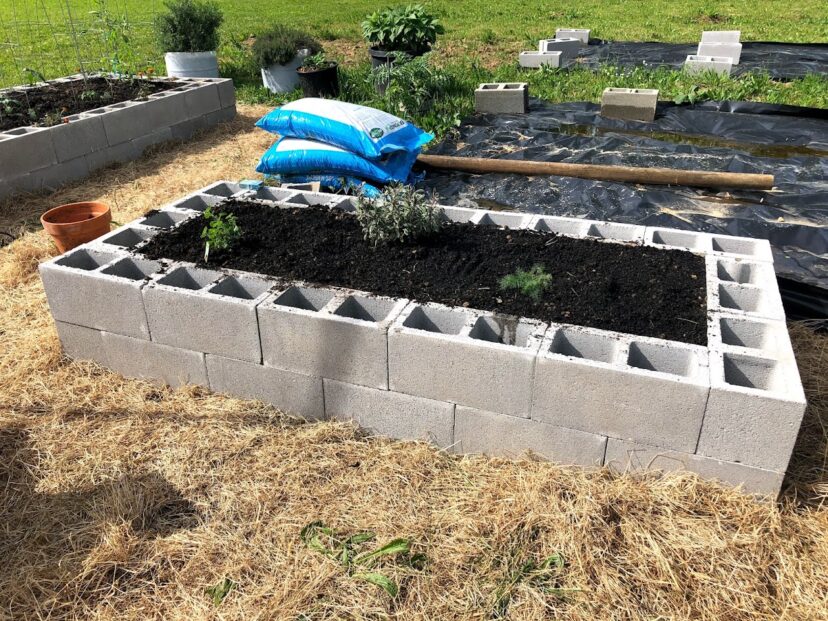 Organic compost is added as the final layer of a raised garden bed.