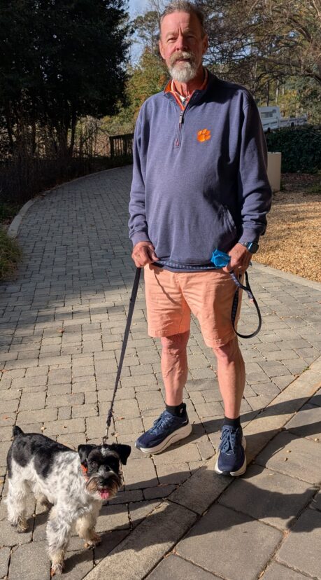 Dog standing with owner along a trail at the South Carolina Botanical Garden.