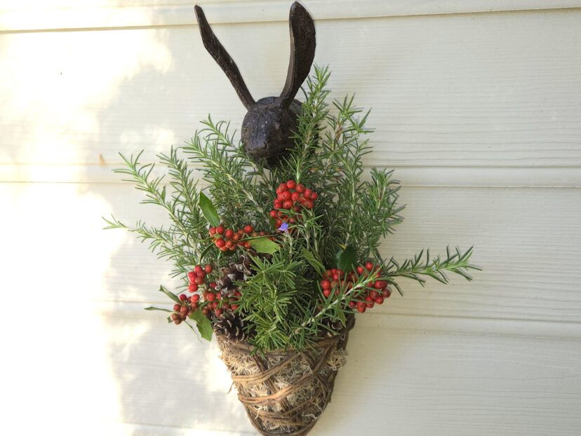 “Finished rosemary holiday basket displayed on a wall.”