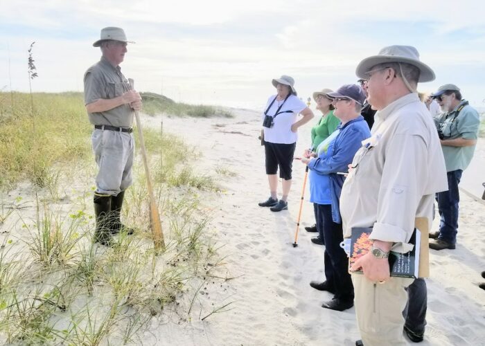 Instructor teaching a group on sandy coastal dunes with sea oats and native vegetation during a South Carolina Native Plant Certificate Program class.