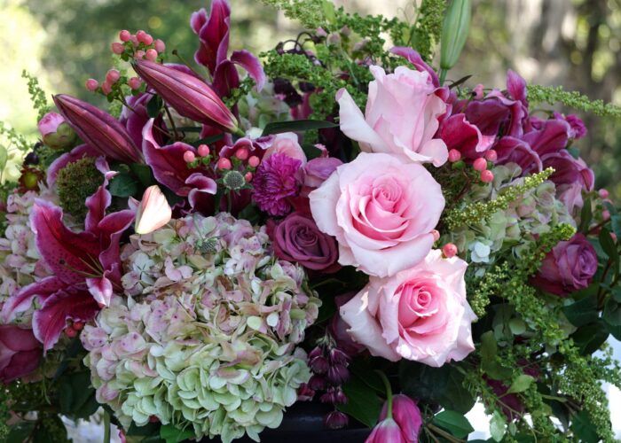 “Pink roses and rubrum lilies arranged with pink hypericum berries and dried hydrangeas in a soft, romantic wedding bouquet.”