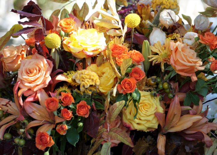 “Warm autumn-toned floral arrangement featuring rich orange and golden-yellow seasonal blooms, styled for a fall wedding.”