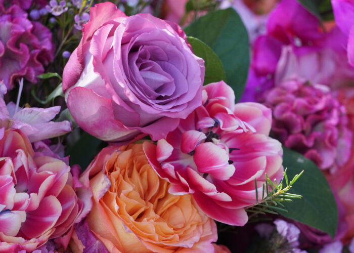 “Roses and tulips arranged together, matching the colors of the bridesmaids’ dresses in the background.”
