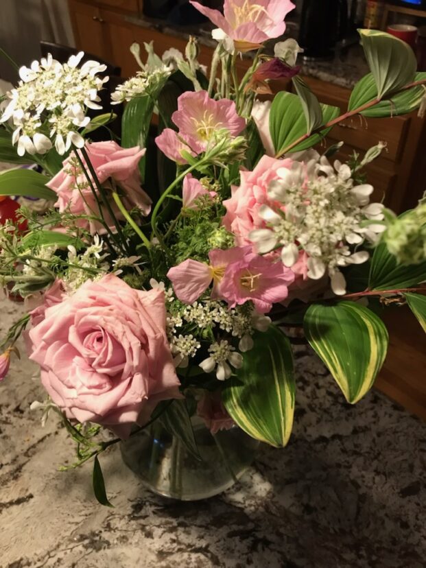 “Floral arrangement featuring soft pink Belinda’s Dream roses mixed with delicate white orlaya, arching stems of Solomon’s seal, and pale yellow evening primrose, arranged in a loose, garden‑style composition.”