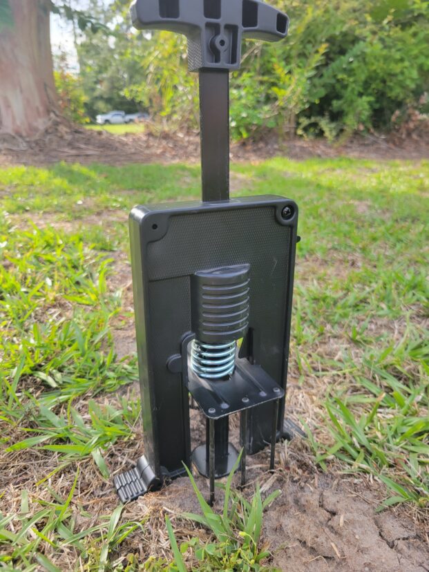 Harpoon mole trap positioned over an active mole tunnel in soil.