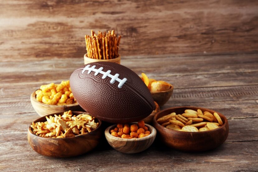 Close up image of a foorball and crunchy snacks.