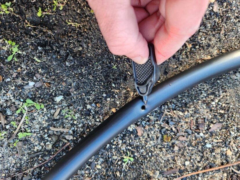 A handheld punch tool making a hole in irrigation tubing for an emitter or barb.