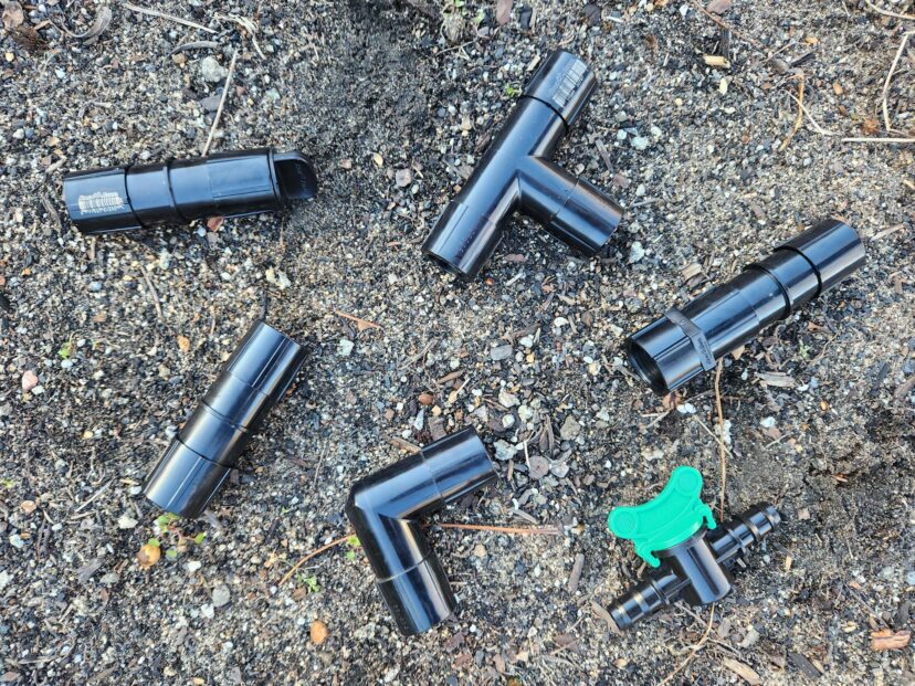 Assorted fittings used to assemble a drip irrigation system, including elbows, tees, end caps, couplers, valves, and adapters.